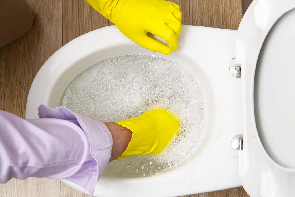 a man unblocking an overflowing toilet